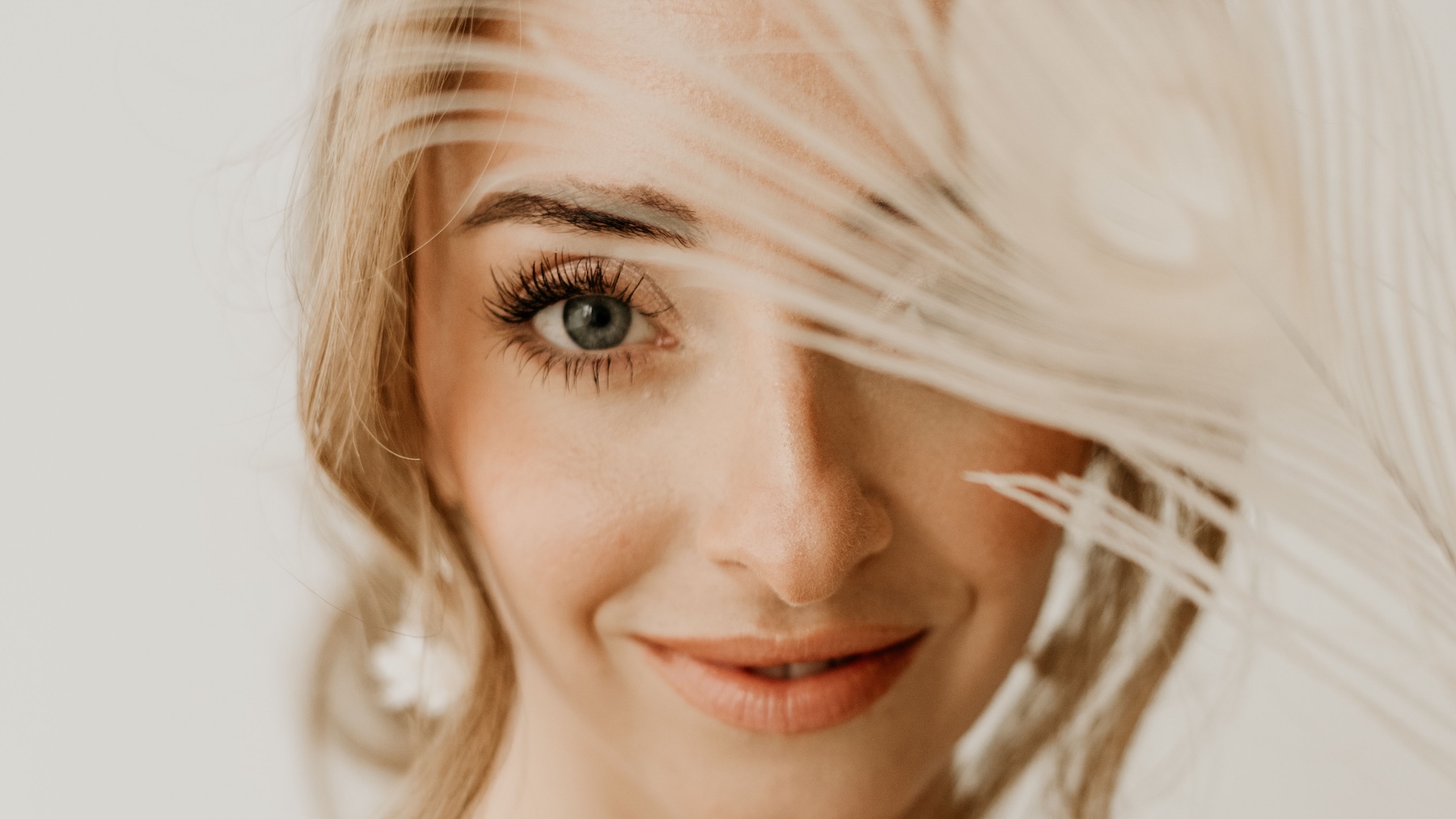 Glückliche Braut mit Feder vor dem Auge